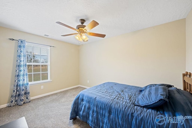 carpeted bedroom with a textured ceiling, a ceiling fan, visible vents, and baseboards