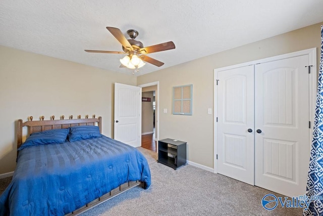 carpeted bedroom with ceiling fan, a textured ceiling, baseboards, and a closet