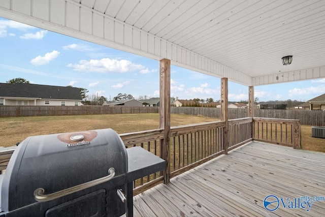 deck featuring a grill, a lawn, and a fenced backyard