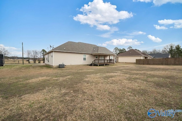 rear view of property featuring central AC unit, fence, a lawn, and a wooden deck