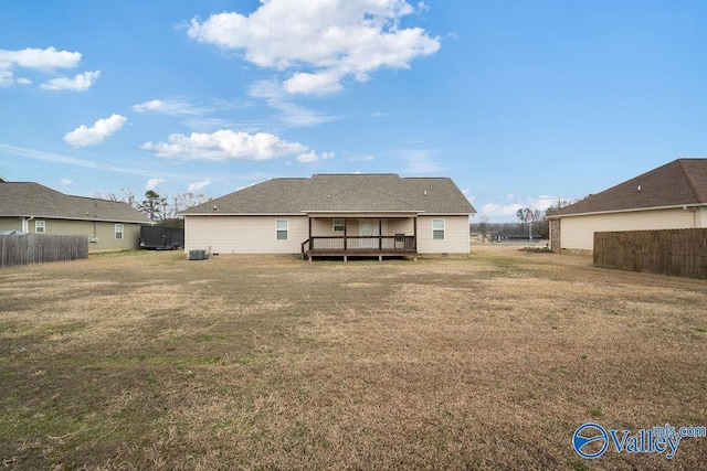 rear view of property featuring fence, a deck, cooling unit, and a yard