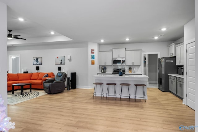 kitchen featuring stainless steel appliances, an island with sink, a breakfast bar area, and light hardwood / wood-style flooring