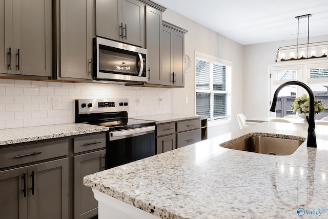 103 Barlow Way, Owens Cross Roads, AL 35763 - kitchen with appliances with stainless steel finishes, decorative backsplash, light stone counters, a chandelier, and pendant lighting