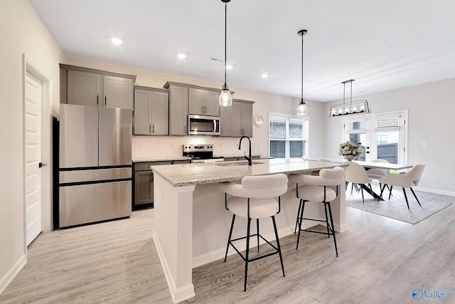 103 Barlow Way, Owens Cross Roads, AL 35763 - kitchen featuring stainless steel appliances, gray cabinets, a kitchen bar, an island with sink, and light stone counters