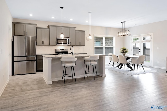 103 Barlow Way, Owens Cross Roads, AL 35763 - kitchen featuring stainless steel appliances, a breakfast bar area, gray cabinetry, an island with sink, and backsplash