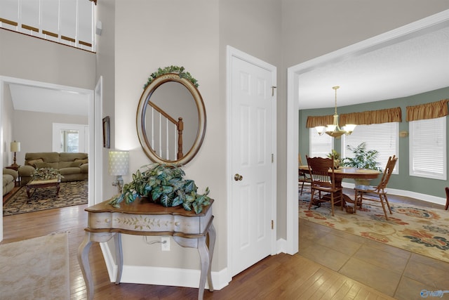 hallway with hardwood / wood-style floors and an inviting chandelier