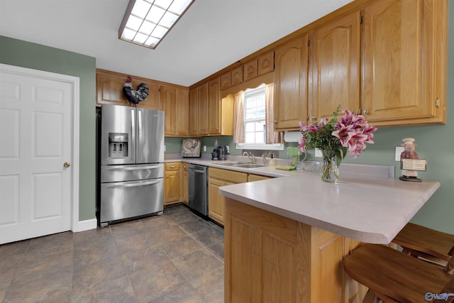 kitchen with sink, a kitchen breakfast bar, appliances with stainless steel finishes, and kitchen peninsula