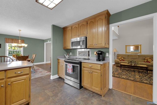 kitchen with a textured ceiling, an inviting chandelier, appliances with stainless steel finishes, and hanging light fixtures