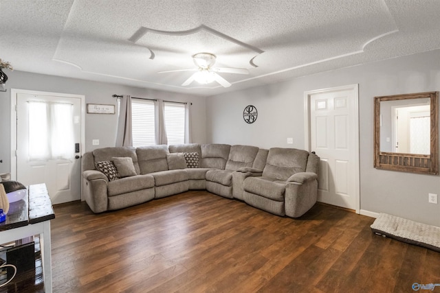 living room with a ceiling fan, dark wood-style flooring, and a textured ceiling