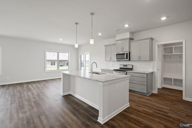 kitchen with gray cabinetry, sink, hanging light fixtures, light stone counters, and stainless steel appliances