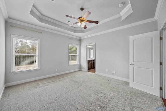 unfurnished bedroom featuring connected bathroom, carpet flooring, baseboards, ornamental molding, and a tray ceiling