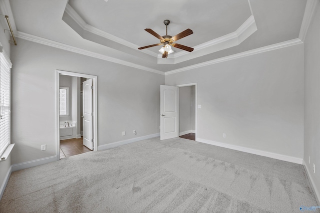 unfurnished bedroom with ensuite bathroom, baseboards, carpet, a raised ceiling, and crown molding