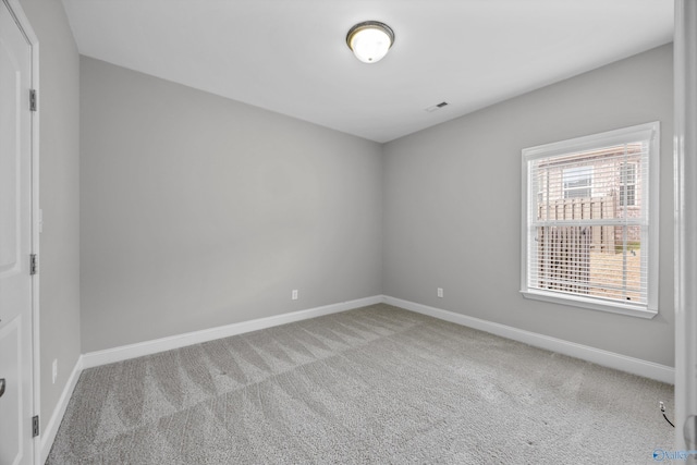 empty room featuring carpet floors, visible vents, and baseboards