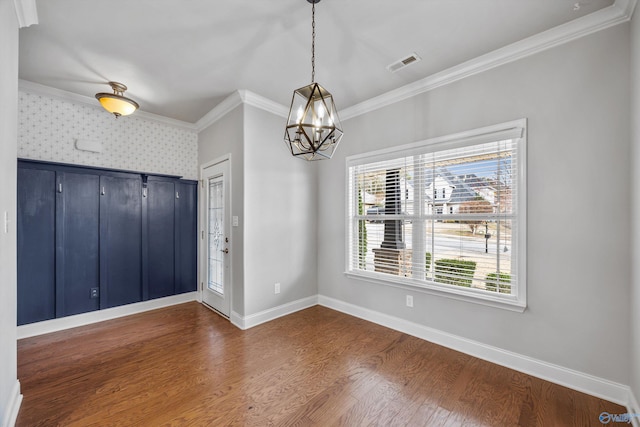 unfurnished dining area featuring baseboards, visible vents, ornamental molding, and dark wood finished floors