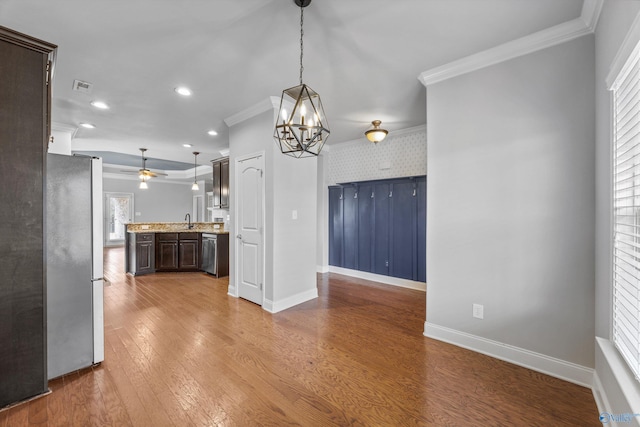 kitchen featuring baseboards, ornamental molding, stainless steel appliances, and wood finished floors