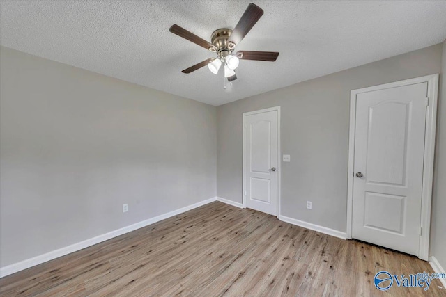 unfurnished bedroom with baseboards, a textured ceiling, wood finished floors, and a ceiling fan