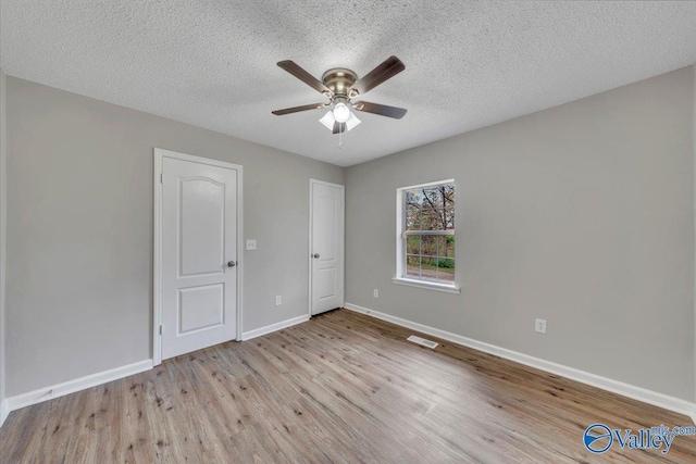 unfurnished bedroom featuring baseboards, visible vents, wood finished floors, and a textured ceiling