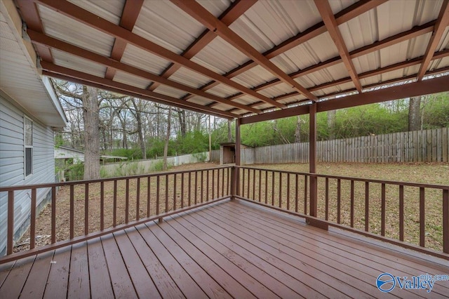 wooden terrace featuring a storage unit, a fenced backyard, and an outbuilding