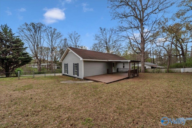 rear view of property featuring fence, a deck, and a lawn