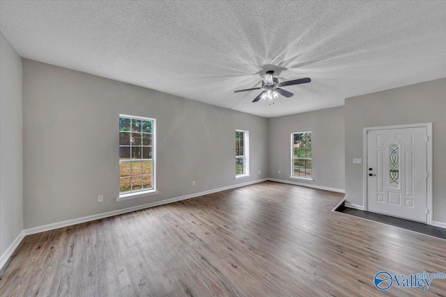 interior space with baseboards, a textured ceiling, wood finished floors, and a ceiling fan