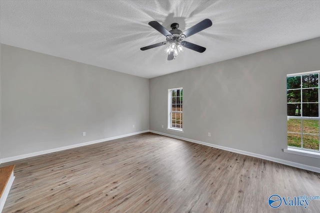 unfurnished room with a ceiling fan, a textured ceiling, baseboards, and wood finished floors