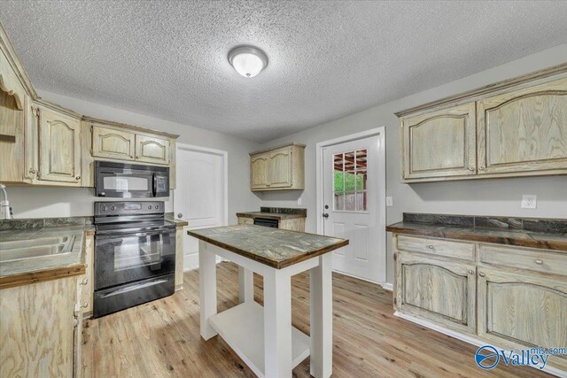 kitchen with a sink, light brown cabinetry, black appliances, and light wood finished floors