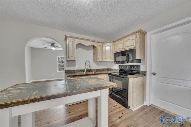 kitchen with light wood-type flooring, a sink, arched walkways, a ceiling fan, and black appliances
