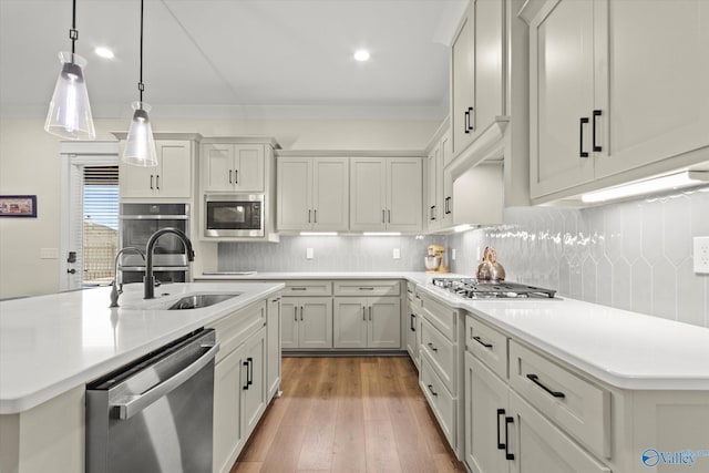 kitchen with hardwood / wood-style floors, tasteful backsplash, sink, a kitchen island with sink, and stainless steel appliances