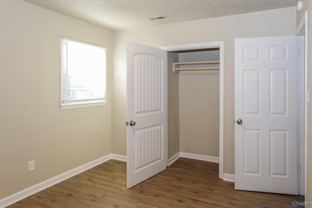 unfurnished bedroom featuring a closet and hardwood / wood-style flooring