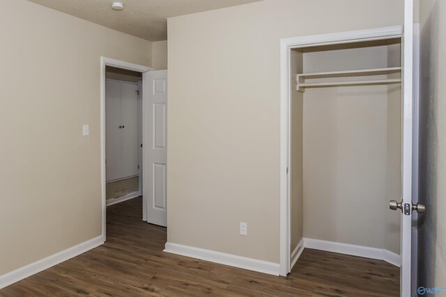 unfurnished bedroom with a closet and dark hardwood / wood-style floors