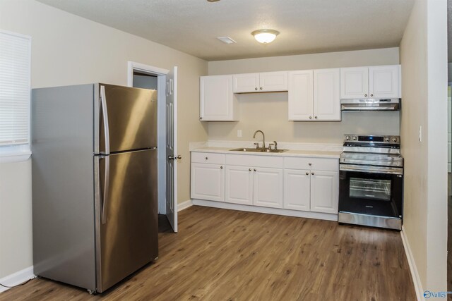 kitchen with white cabinetry, appliances with stainless steel finishes, hardwood / wood-style floors, and sink