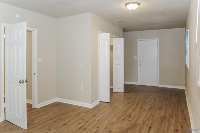 unfurnished room with light hardwood / wood-style floors and a textured ceiling