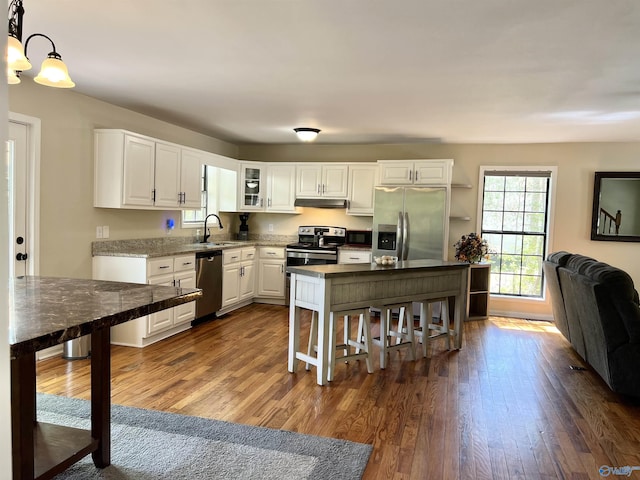 kitchen with white cabinetry, appliances with stainless steel finishes, dark wood finished floors, and a breakfast bar