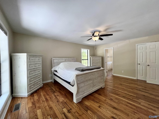 bedroom with dark wood-style flooring, baseboards, ensuite bathroom, visible vents, and ceiling fan
