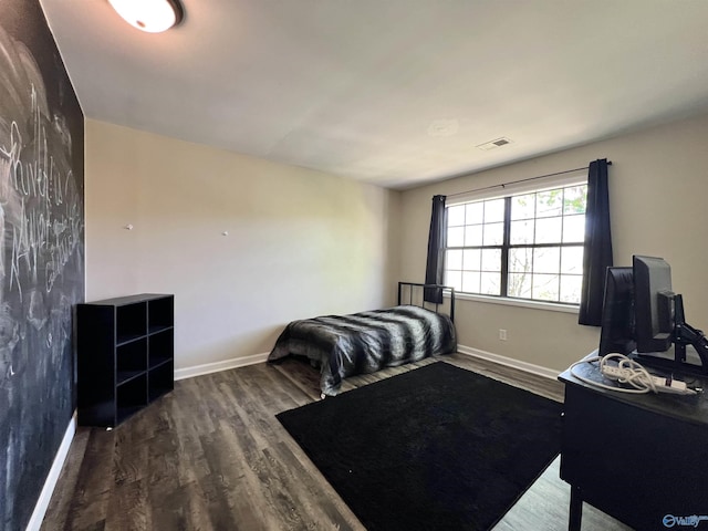 bedroom with wood finished floors, baseboards, and visible vents
