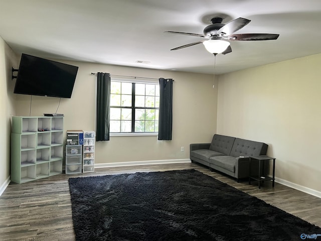 living room featuring wood finished floors, baseboards, a ceiling fan, and visible vents