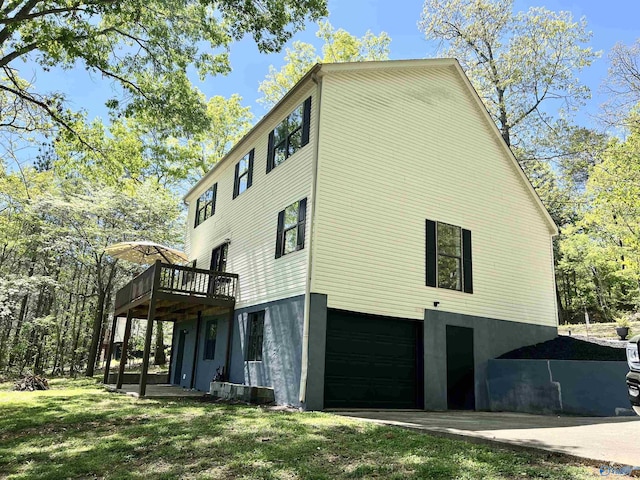 view of property exterior with concrete driveway, a yard, a garage, and a wooden deck