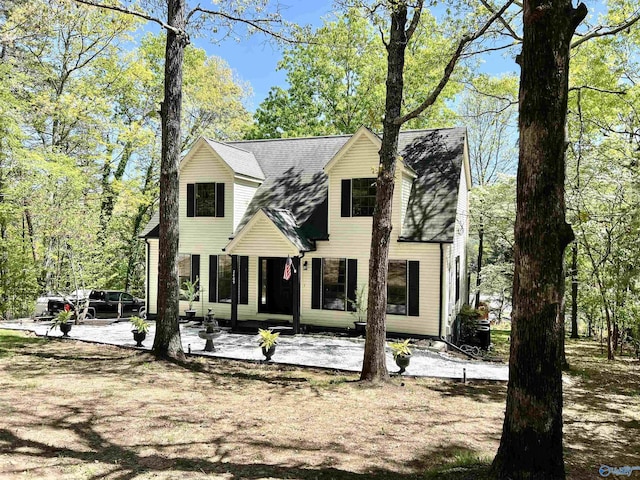 view of front facade with a patio and roof with shingles