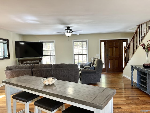 living area with stairs, baseboards, a ceiling fan, and wood finished floors