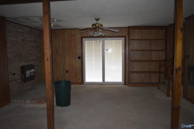 unfurnished living room with a ceiling fan, a textured ceiling, carpet floors, wooden walls, and a wood stove