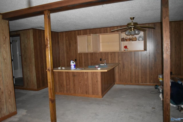 interior space with wooden walls, ceiling fan, and a textured ceiling