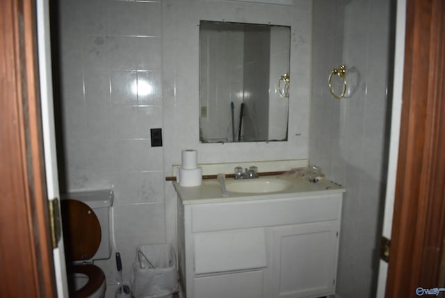 bathroom with vanity, tile walls, and toilet