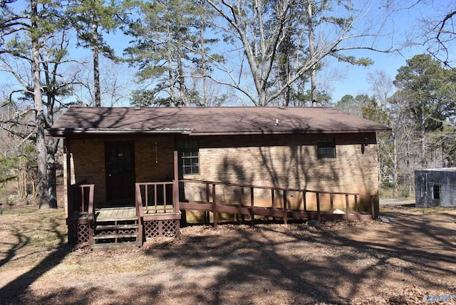 rear view of property featuring a wooden deck and brick siding