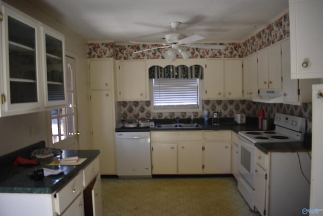 kitchen with white appliances, dark countertops, range hood, and a sink