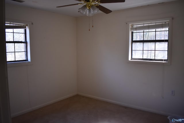 carpeted spare room featuring visible vents, baseboards, and a ceiling fan