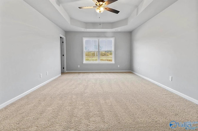 carpeted spare room featuring a tray ceiling and ceiling fan