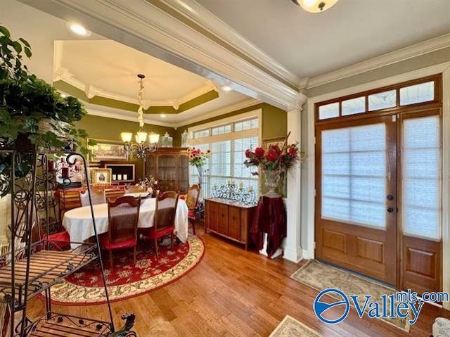 dining room featuring french doors, a raised ceiling, crown molding, hardwood / wood-style flooring, and a notable chandelier