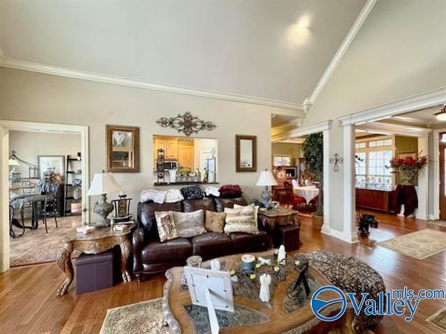 living room featuring ornate columns, hardwood / wood-style flooring, lofted ceiling, and ornamental molding