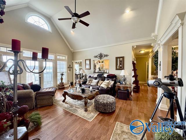 living room featuring hardwood / wood-style floors, high vaulted ceiling, ceiling fan, and ornamental molding