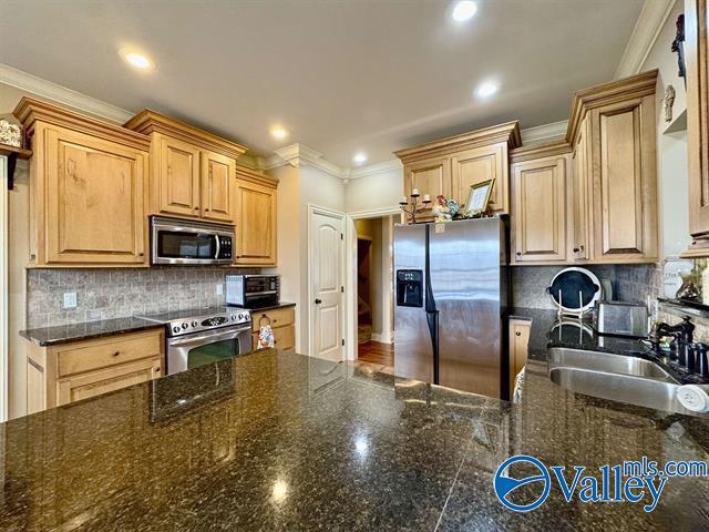 kitchen featuring backsplash, light brown cabinetry, sink, and stainless steel appliances